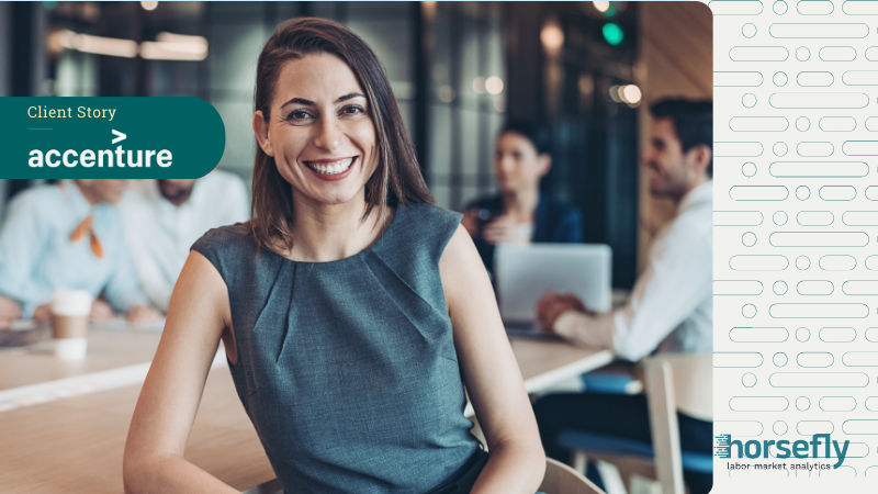 Image shows a business woman leaning on a desk and smiling at the camera