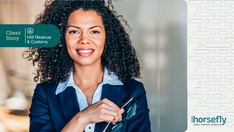 Image shows a business woman holding a pair of glasses and smiling at the camera