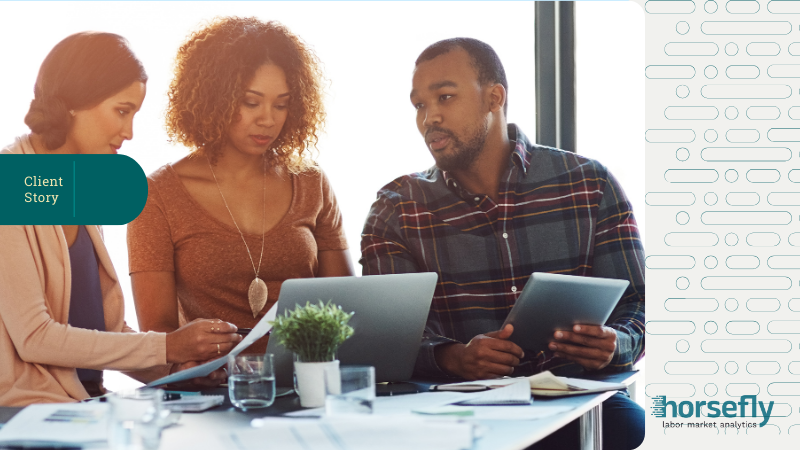 Image shows a group of three people working and talking over laptops and tablets