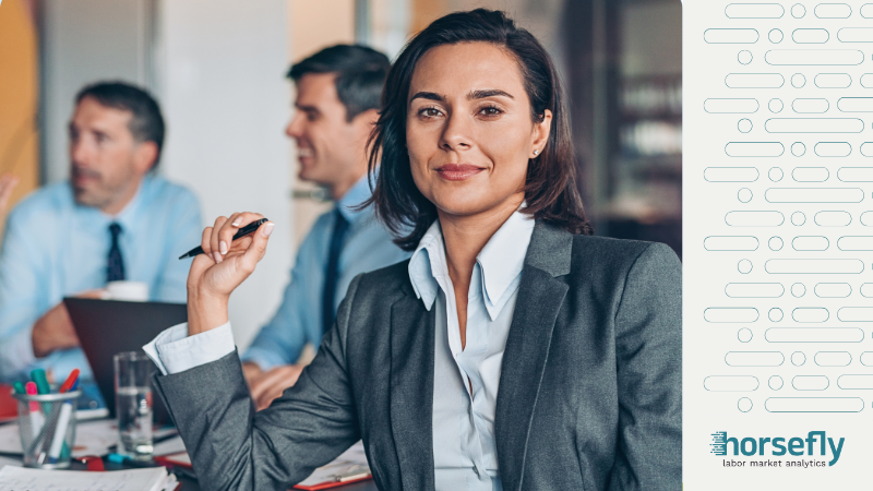 Image shows a woman looking confidently at the camera with a pen in her hand for the blog - Empowering Leadership with Accurate Labor Market Data