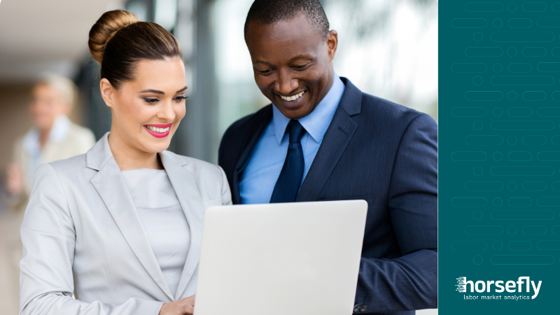 Image shows a man and a woman happily discussing work on a laptop for the blog - Choosing Your Labor  Market Analytics Platform & Developing Best Practices